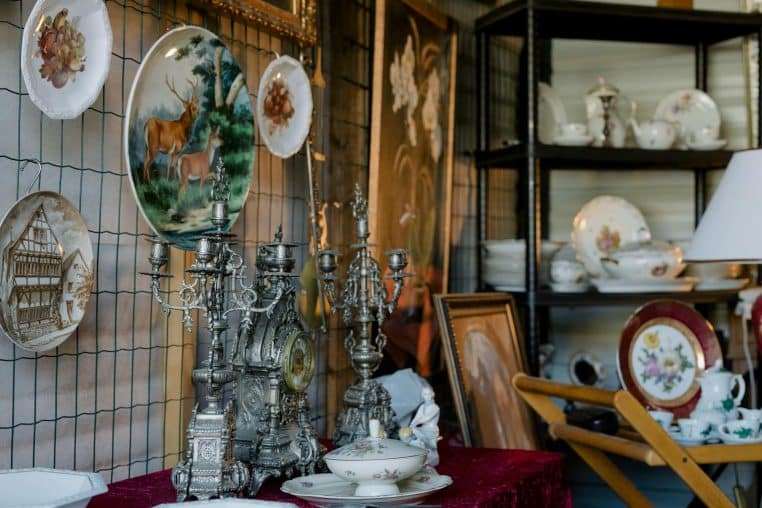 Charming assortment of vintage plates, candelabras, and tableware on display indoors.