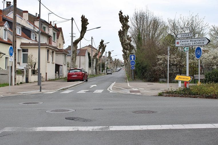 Avenue urbaine avec bande cyclable et panneau C12 indiquant le sens unique.