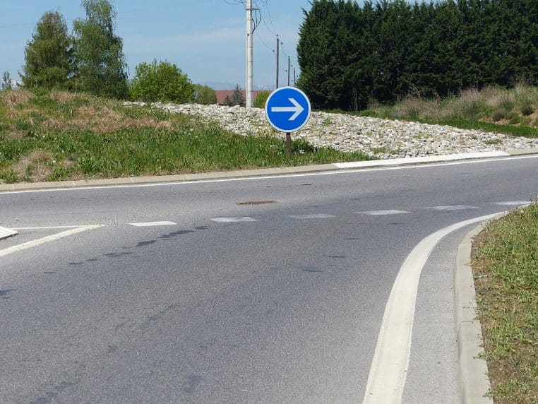 Panneau rond bleu flèche vers le haut B21-1 à une intersection de Haute-Savoie.