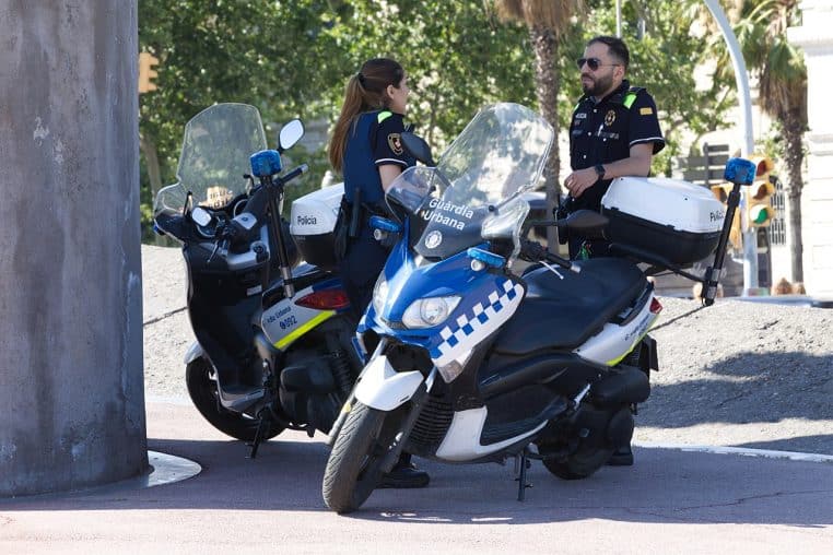Deux policiers urbains sur des motos de service dans une rue.