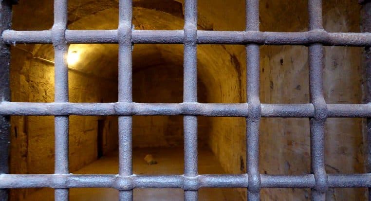 Intérieur d’un cachot aux barreaux épais.