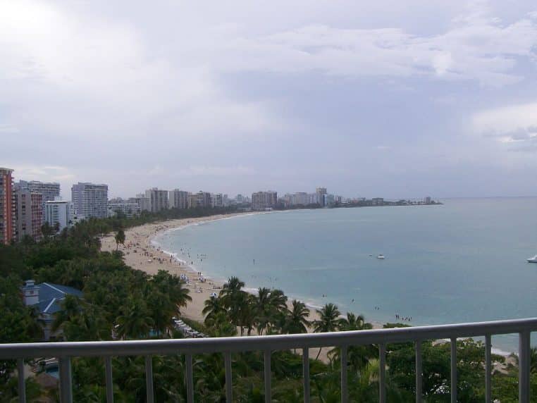 Large plage de sable à Isla Verde avec cocotiers et mer calme.