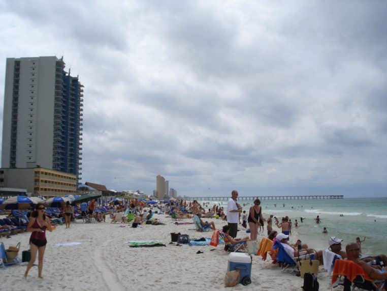 Plage très fréquentée à Panama City Beach, avec baigneurs dans l’eau et parasols.