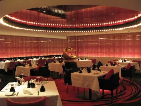 Salle de restaurant moderne avec tables nappées et chaises confortables.