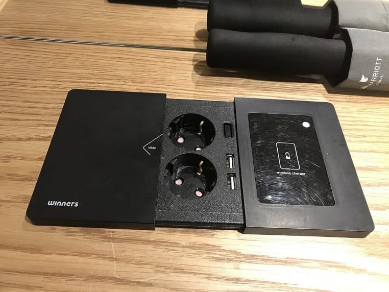 Smartphone en charge sans fil sur table avec ports USB visibles.