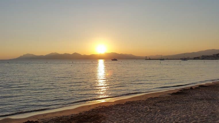 Plage de Cannes avec parasols au coucher de soleil.