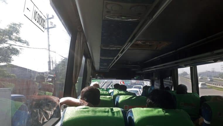 allée centrale d’un bus avec sièges et voyageurs.