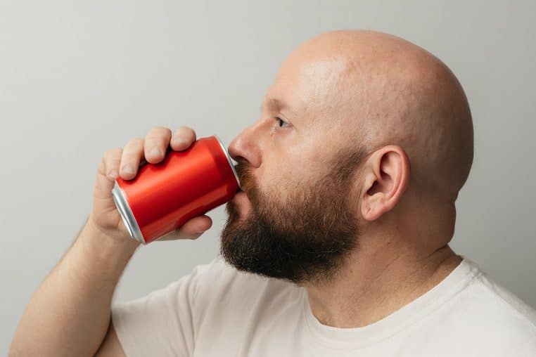 Homme avec calvitie boit une soda