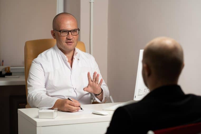 Médecin discutant avec un patient dans un cabinet, plan horizontal.