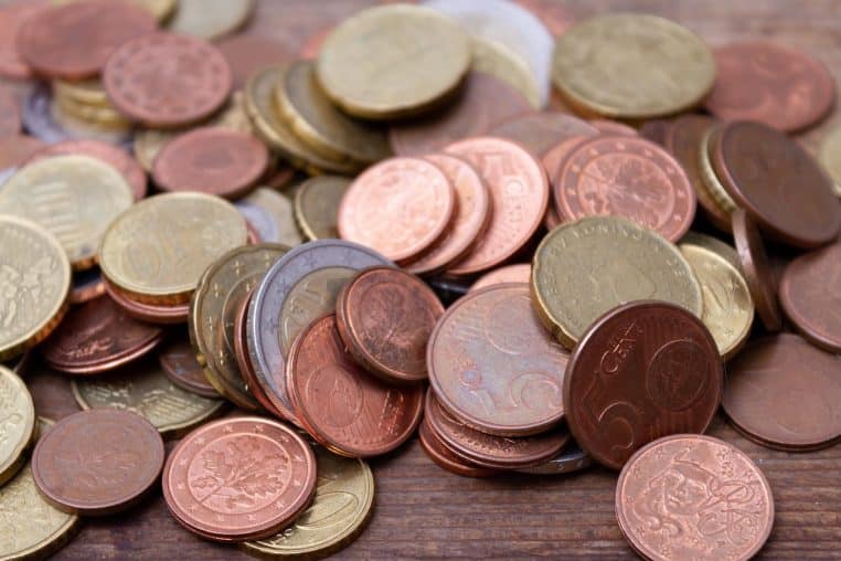 Petites piles de pièces argentées alignées sur un fond neutre.