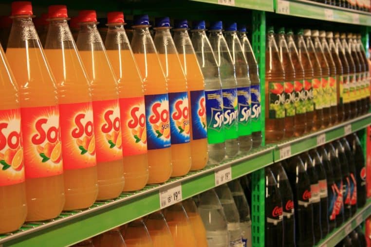 bouteilles de boissons gazeuses alignées dans un rayon de supermarché