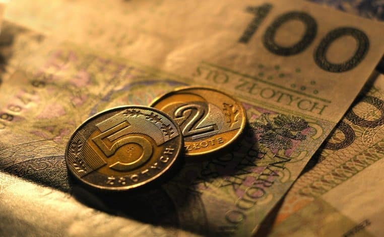 Plusieurs pièces de monnaie et billets étalés sur une surface sombre.