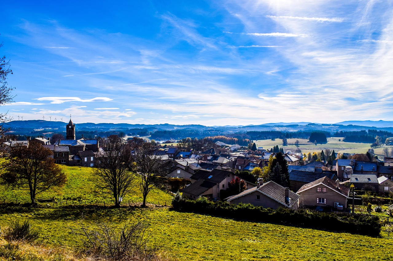 Plateau ardéchois avec village et reliefs, grande route de campagne au premier plan.