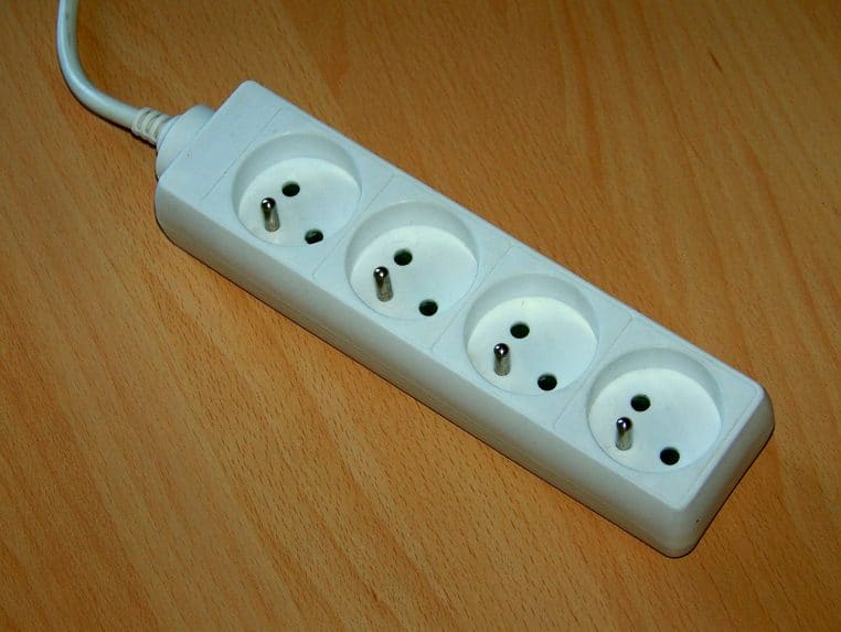 Multiprise française de quatre prises branchée au secteur, vue rapprochée