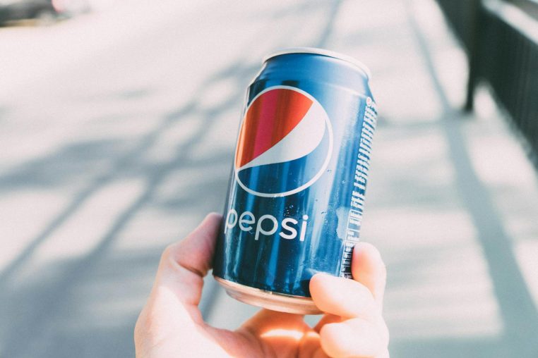 Refreshing Pepsi can held in hand on a sunny day. Perfect for advertisements.