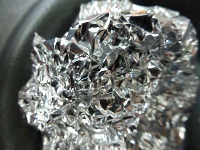 Feuille de papier aluminium compressée, texture froissée brillante.