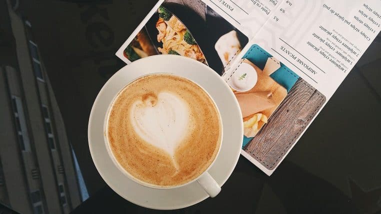 Tasse de café blanche posée sur une recette imprimée.