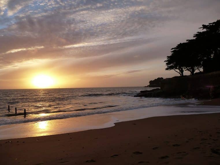 Plage de Pornic avec soleil couchant et ciel orangé.