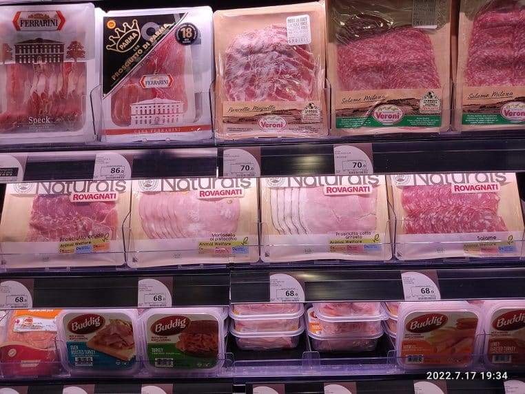 Étagère de supermarché avec barquettes de jambon tranché.