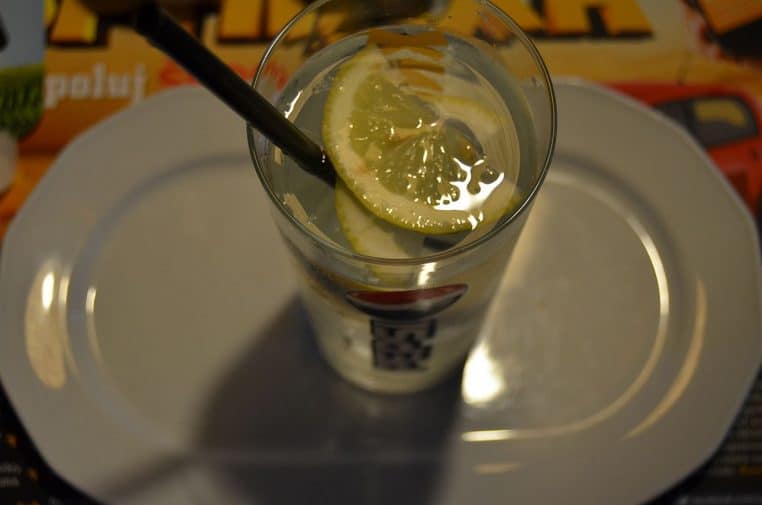 verre d’eau avec rondelles de citron sur fond clair.