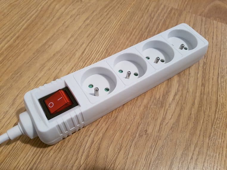 Multiprise française blanche avec interrupteur rouge, posée sur un bureau