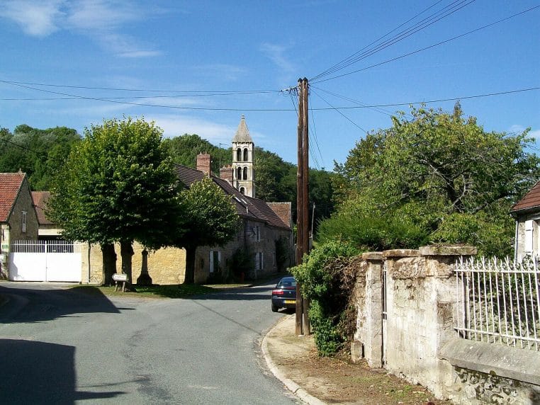 Place du village de Rhuis (Oise) avec calvaire et église, sans excès de panneaux.