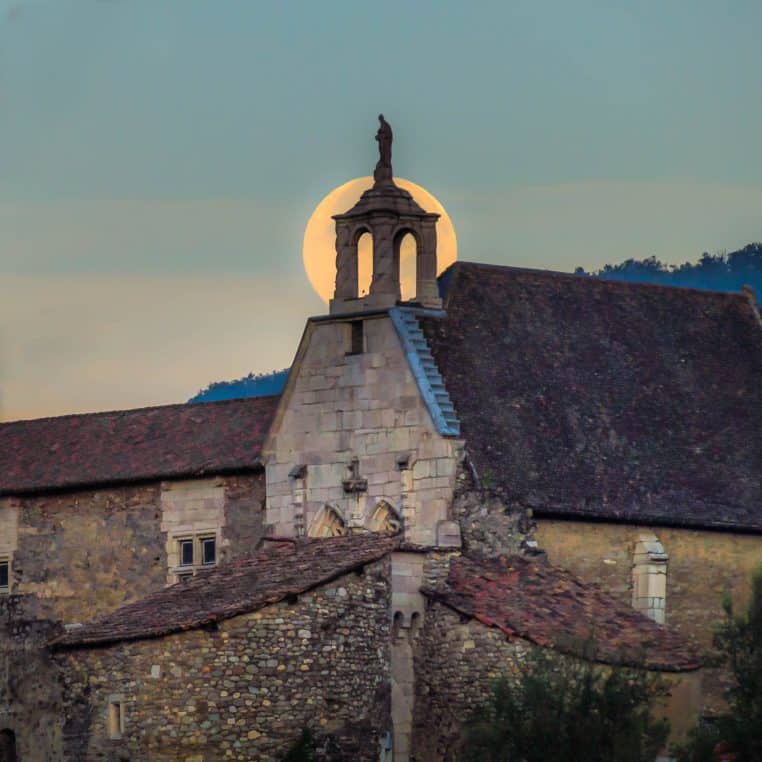 Pleine lune derrière une statue d’église en France.
