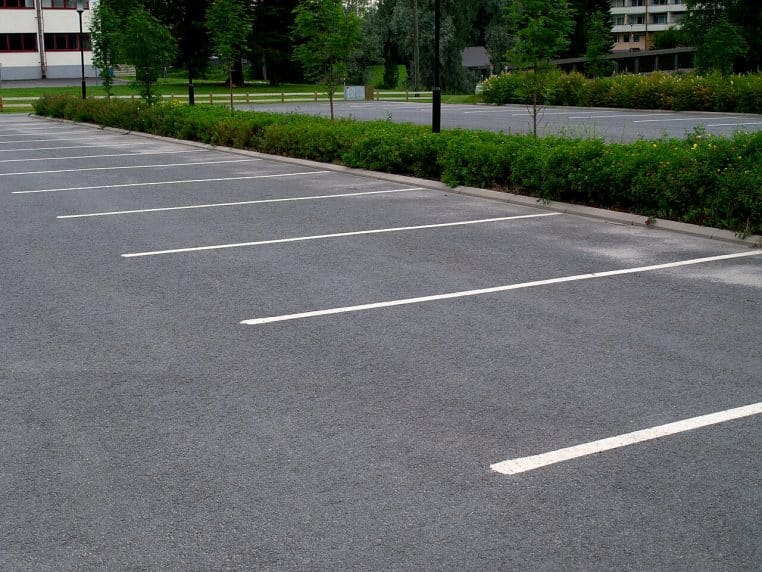 Marquage blanc délimitant une place de parking sur enrobé, vue rapprochée.