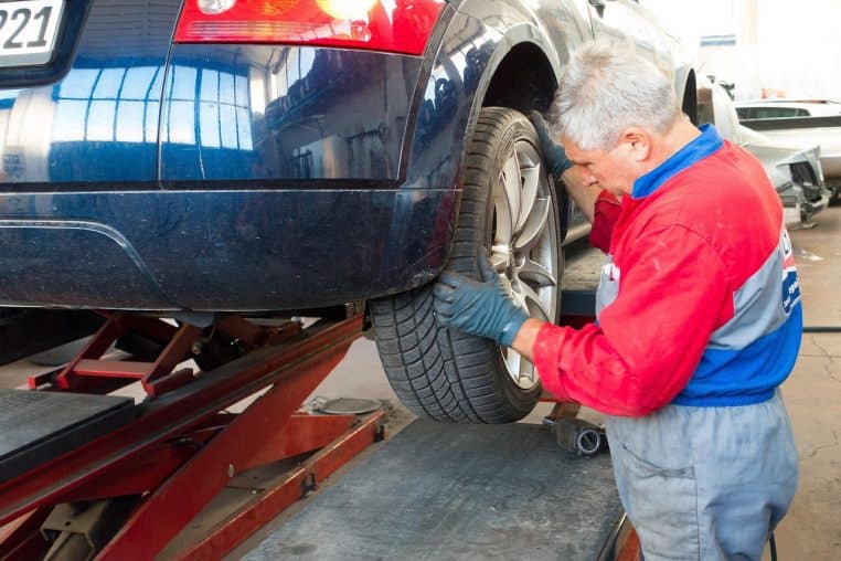 Mécanicien contrôlant une roue avant dans un atelier automobile
