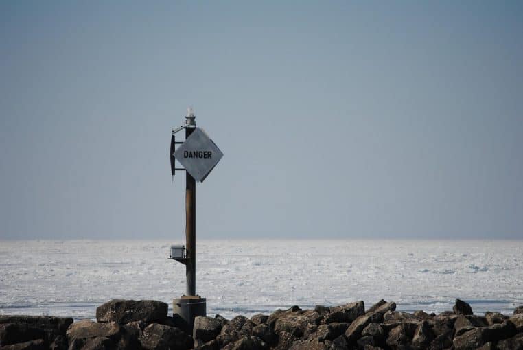 Panneau d’avertissement « Danger » planté sur une plage avec vagues au large
