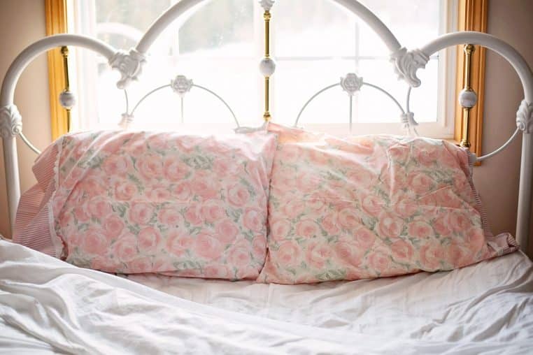 Lit défait le matin avec draps clairs et lumière naturelle.