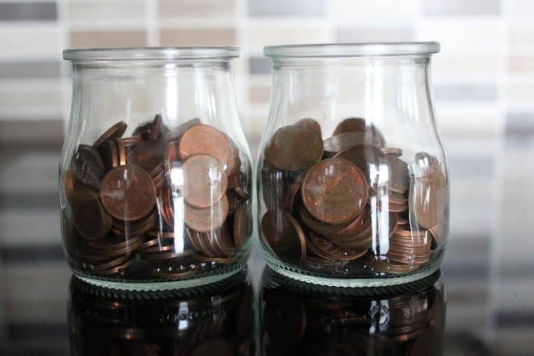 pièces en euros dans un récipient en verre évoquant un livret d’épargne.