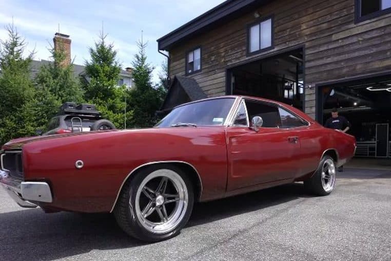 Dodge Charger 1968 rouge sortant de l’atelier AMMO NYC après restauration, vue trois-quarts, jantes alliage, garage ouvert au second plan.
