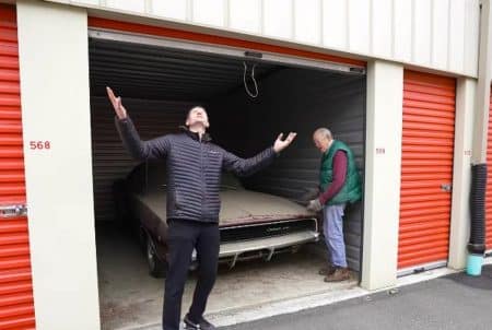Dodge Charger 1968 rouge sortant de l’atelier AMMO NYC après restauration, vue trois-quarts, jantes alliage, garage ouvert au second plan.