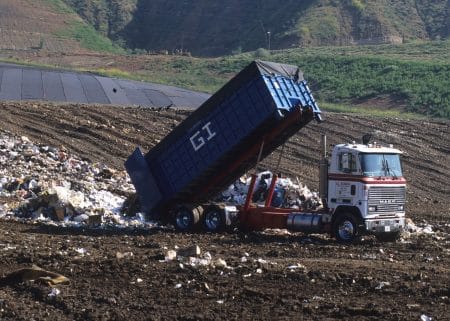 Camion-benne au milieu d’un amas de déchets en décharge.