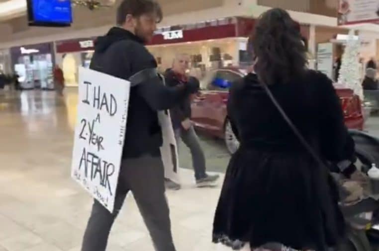 Homme infidèle obligé de porter une pancarte dans un centre commercial
