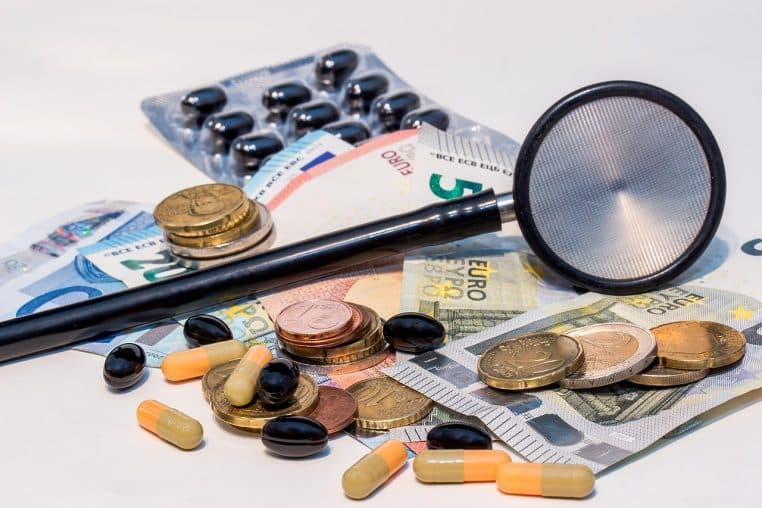 médicaments et stéthoscope posés sur des billets en euros