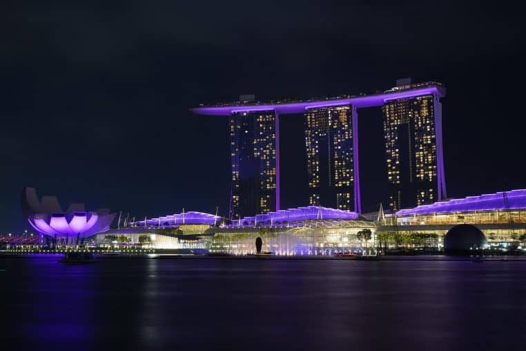 Vue nocturne sur Marina Bay, hôtels et gratte-ciel illuminés.