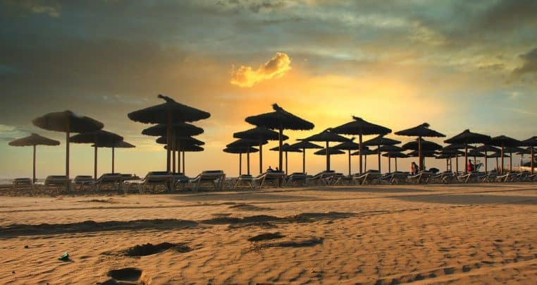 Rangée de parasols sur une plage espagnole au lever du soleil.