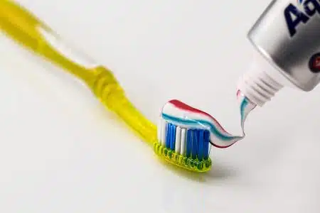 Brosse à dents posée sur un lavabo avec dentifrice déposé sur les poils