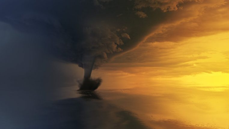A powerful tornado over the ocean during a dramatic sunset, capturing the storm's intensity and beauty.