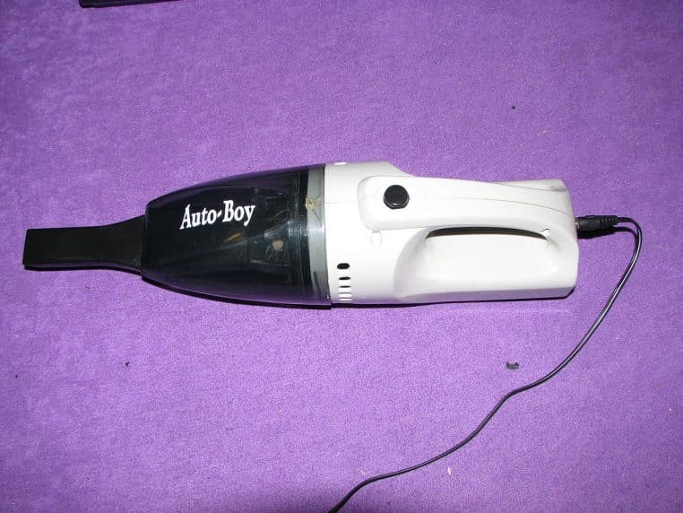 Petit aspirateur à main filaire noir et blanc sur tapis violet
