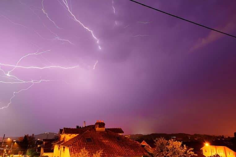 Éclairs zébrant le ciel au-dessus des toits de Belfort, ambiance violette.