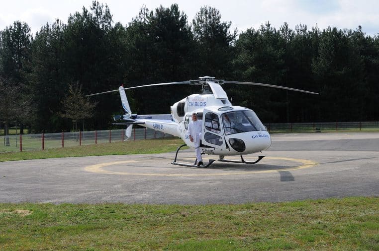 Hélicoptère du SAMU 41 posé près d’un bâtiment hospitalier, ciel dégagé, marquages médicaux visibles sur la carlingue en stationnement.