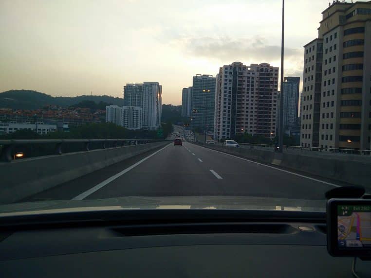 Grande artère de Kuala Lumpur au crépuscule avec ciel bleu profond.
