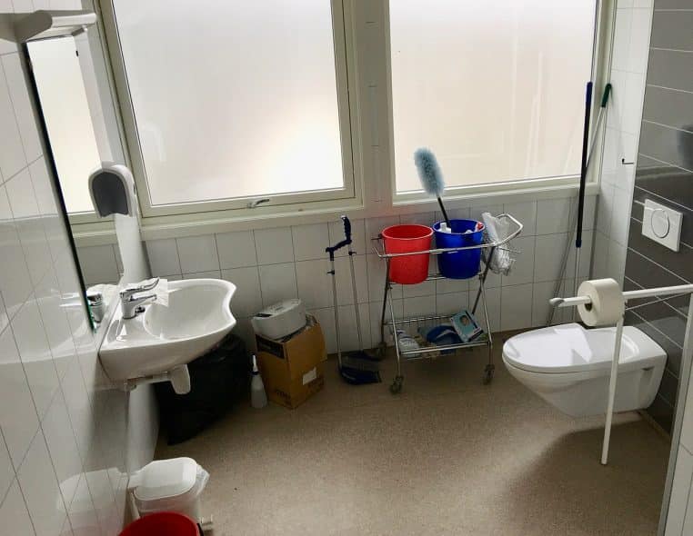 Petite pièce d’école avec cuvette, lavabo et miroir ; ensemble clair et soigné montrant l’état attendu après nettoyage.