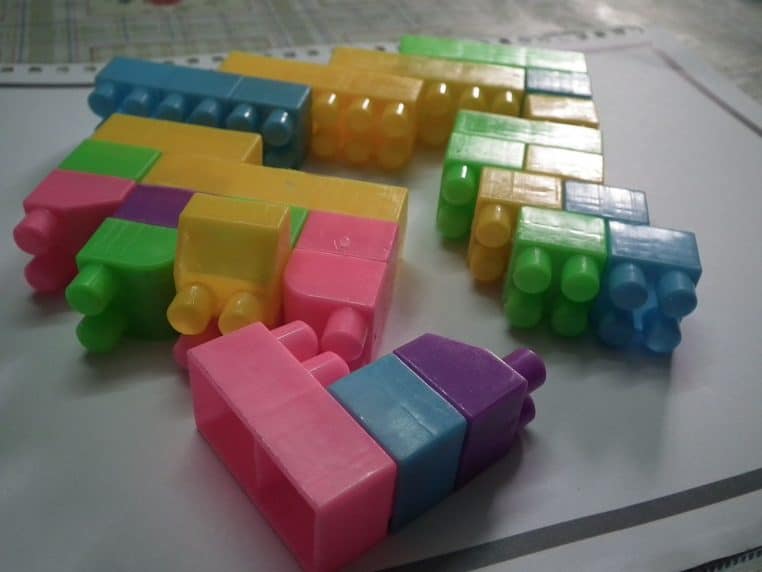 Blocs de construction multicolores dispersés sur une surface, représentant des jouets d’enfants courants.