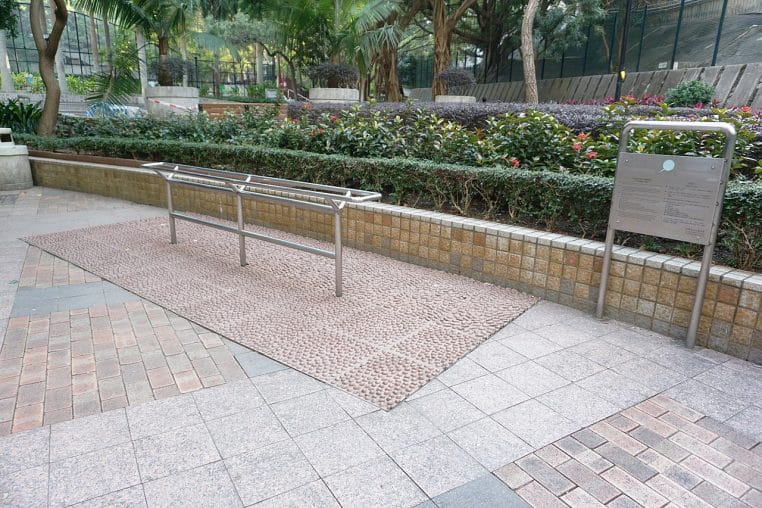 Parc urbain avec chemin de marche aménagé, mosaïque au sol et végétation dense autour.