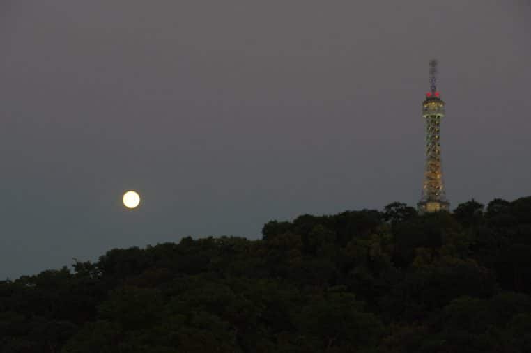Lune brillante au-dessus de Prague au crépuscule, atmosphère urbaine et romantique propice aux tensions relationnelles.