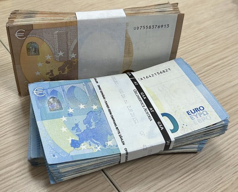 Liasses de billets de 20 et 50 euros sous bande de conditionnement, prêtes pour un dépôt bancaire.